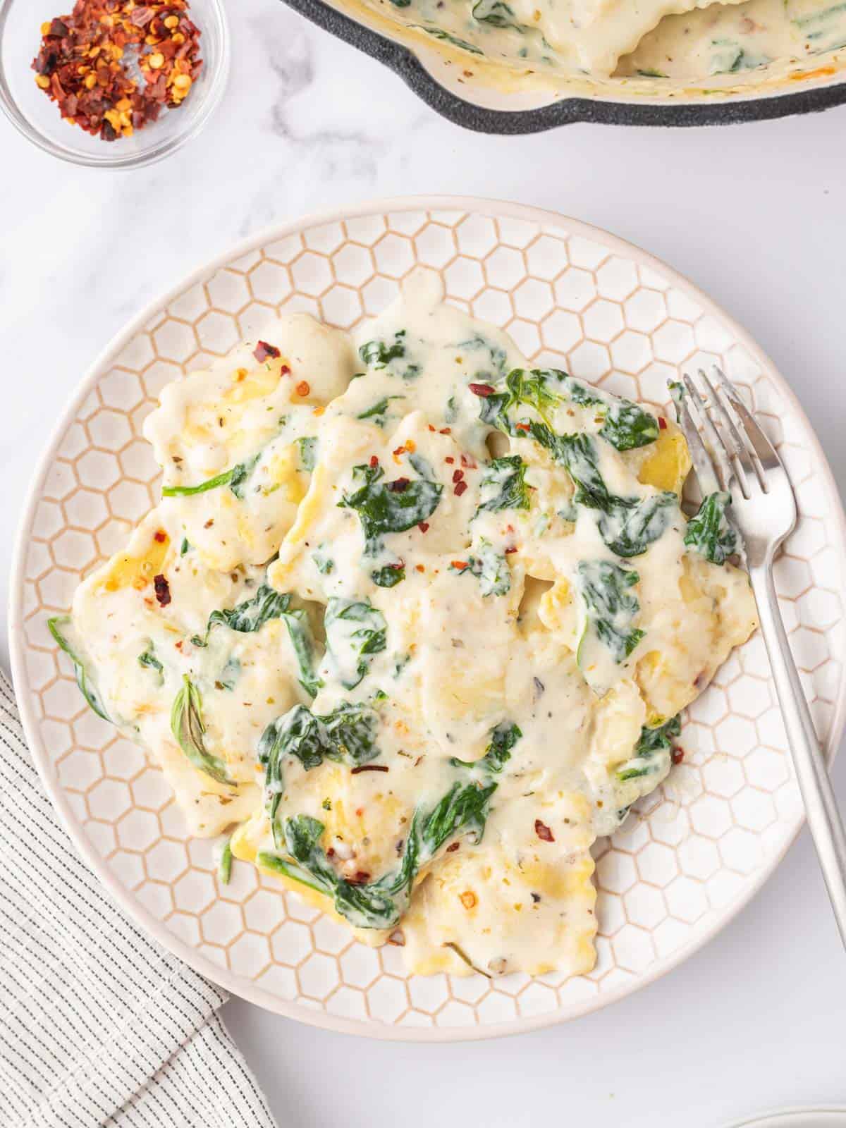 Spinach and cheese ravioli on a plate with a fork.