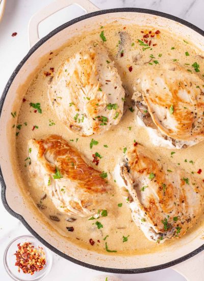 Mushroom Stuffed Chicken Breast in a white skillet with a creamy sauce..