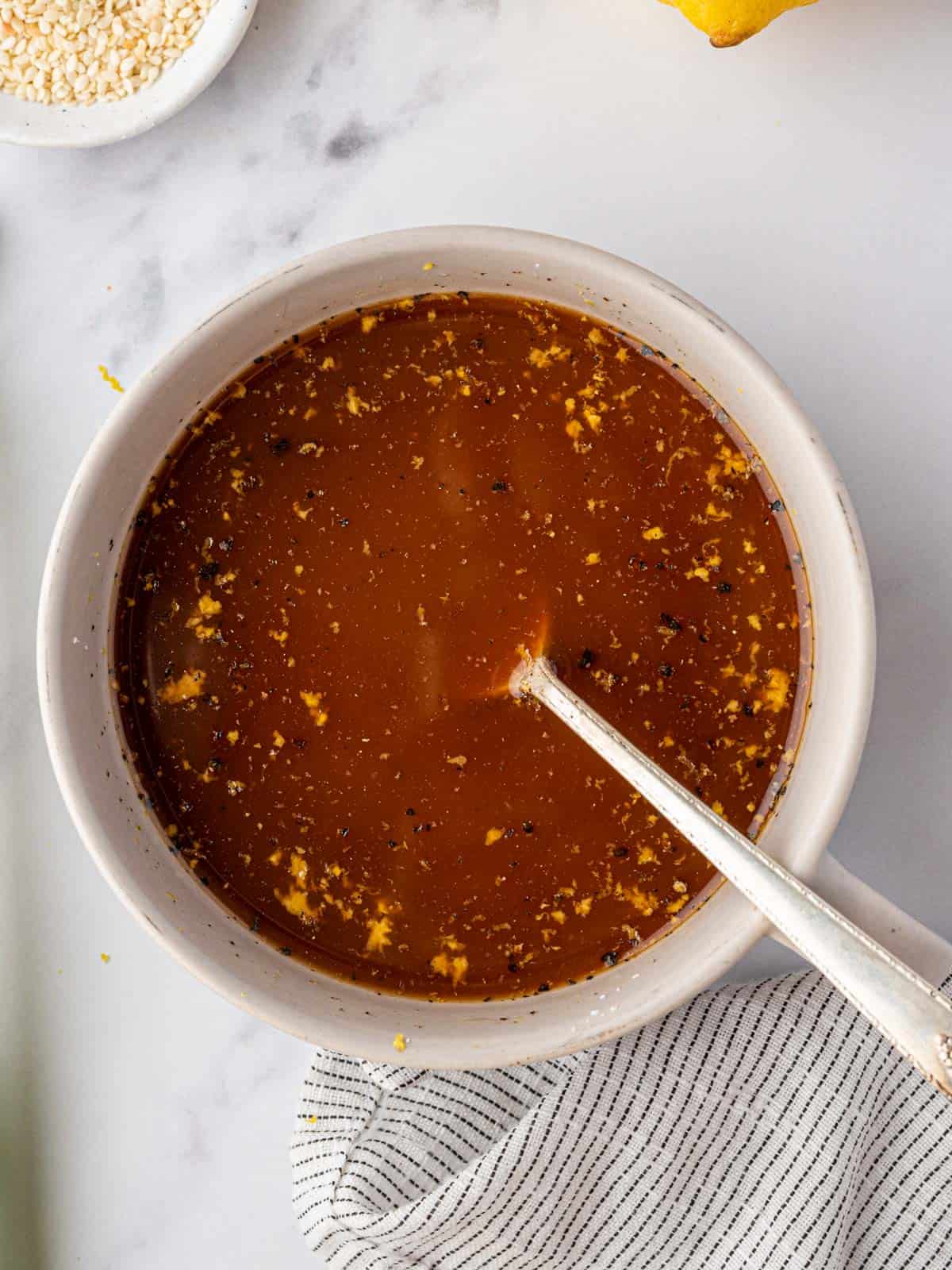 A white bowl of Chinese lemon sauce with a silver spoon.