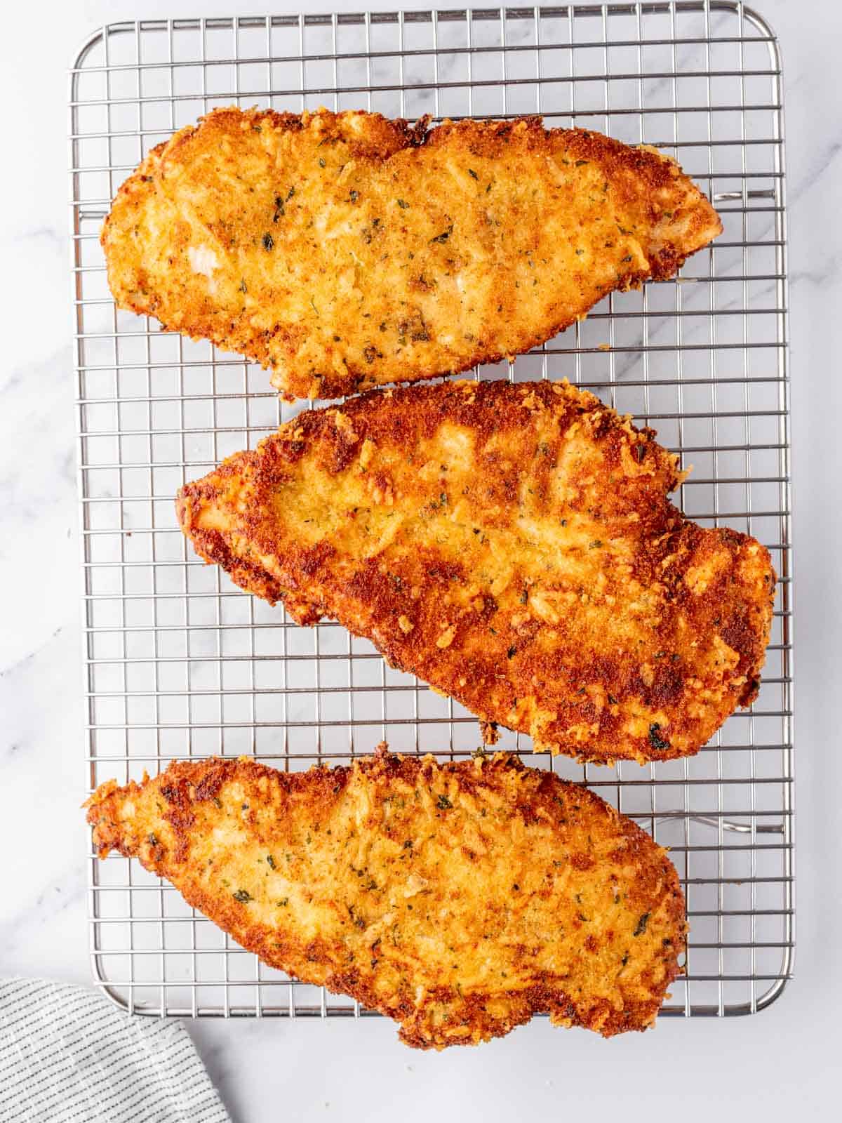Parmesan crusted chicken rests on a wire rack