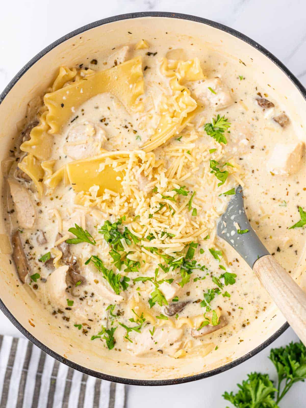 A spoon stirring a pot of white lasagna soup.