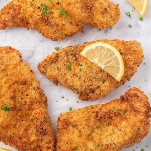 Crispy chicken cutlets with lemon slices and parsley.