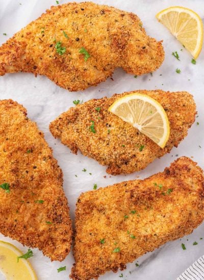Crispy chicken cutlets with lemon slices and parsley.