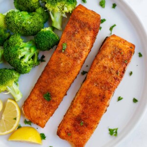 two pieces of air fried salmon on a plate with broccoli