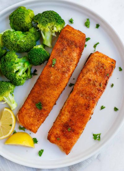 two pieces of air fried salmon on a plate with broccoli