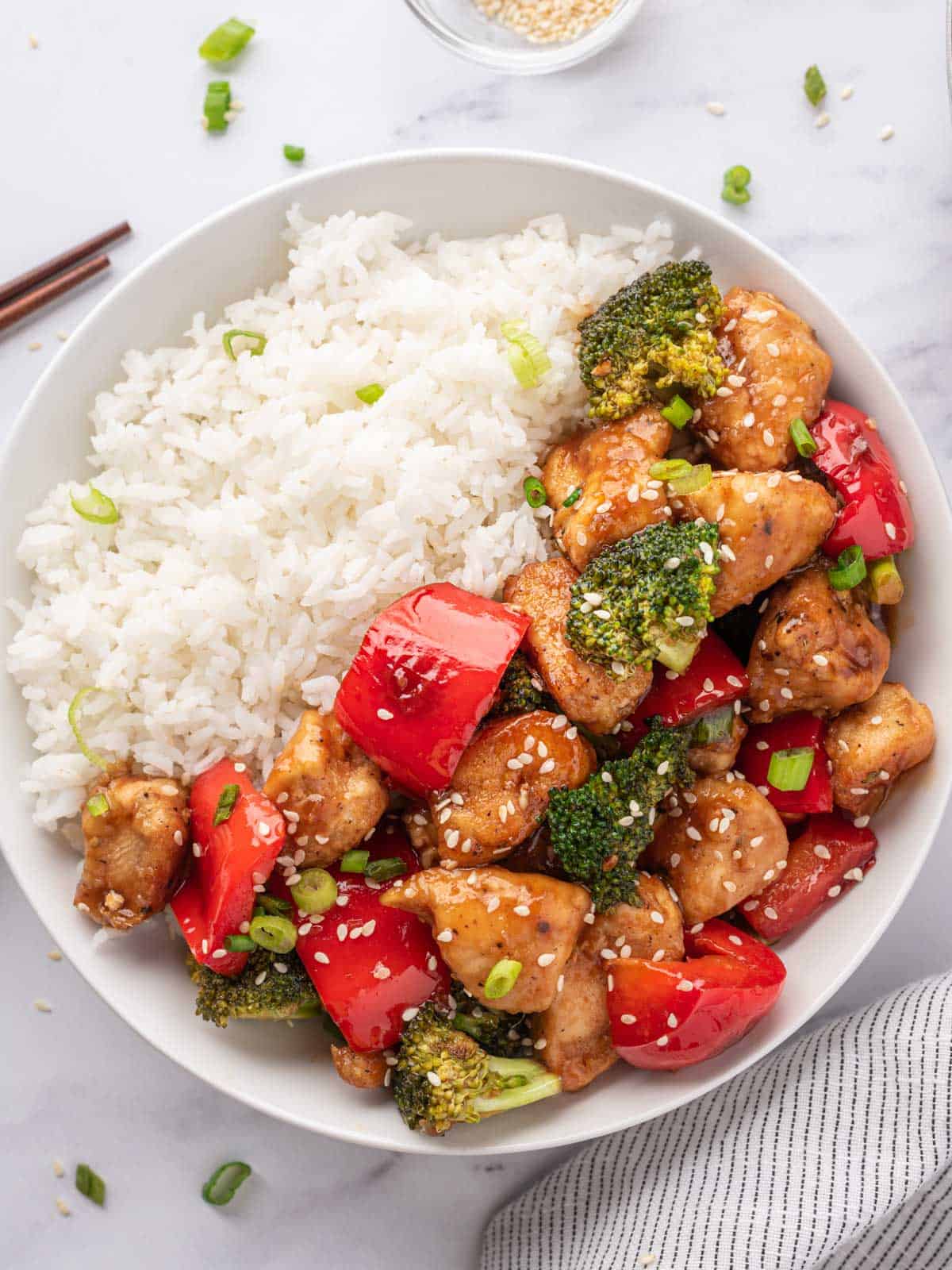 White bowl with rice and topped with Teriyaki chicken stir fry recipe.