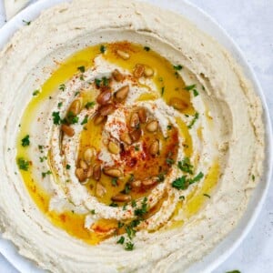 lebanese hummus in a plate, topped with olive oil, paprika, pine nuts