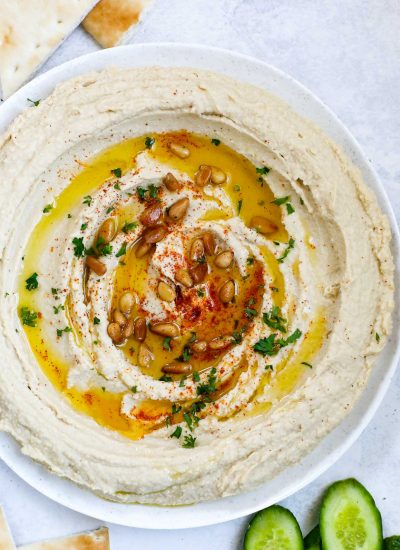 lebanese hummus in a plate, topped with olive oil, paprika, pine nuts