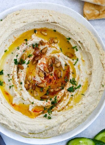 lebanese hummus in a plate, topped with olive oil, paprika, pine nuts