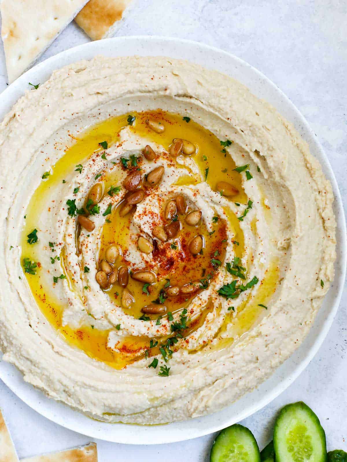 lebanese hummus in a plate, topped with olive oil, paprika, pine nuts