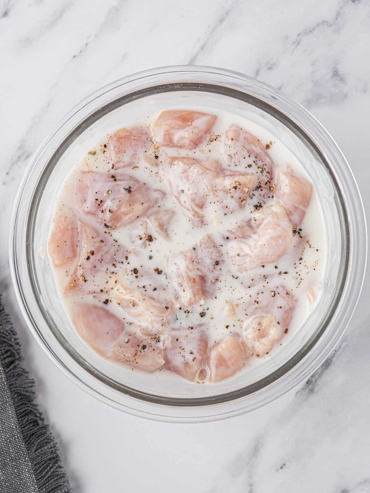 Cubed chicken tenders marinating in buttermilk.