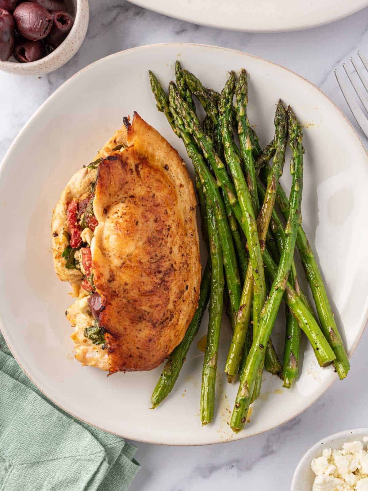 A plate of asparagus with Mediterranean stuffed chicken breast.