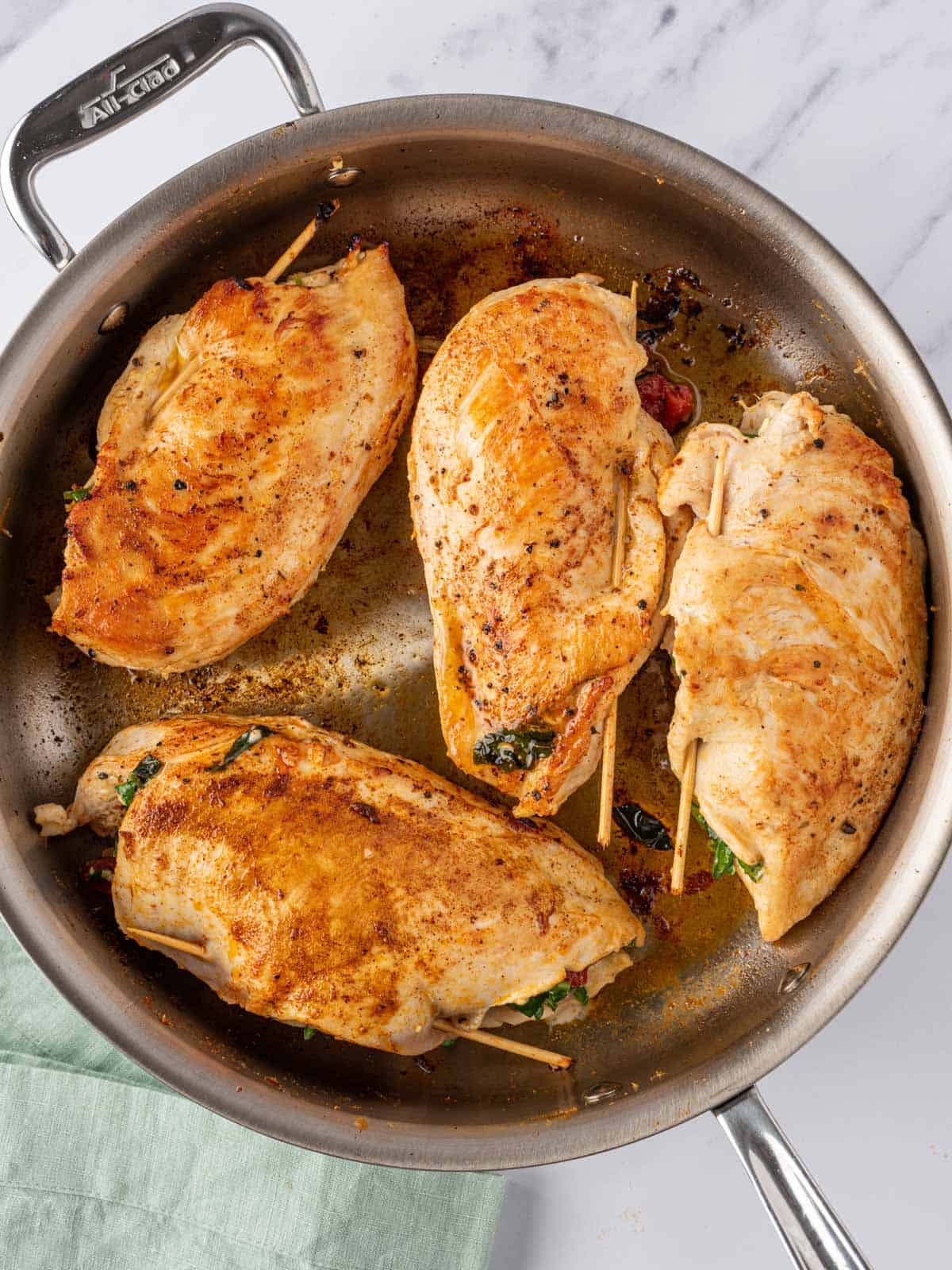 Mediterranean stuffed chicken breasts seared in a pan.