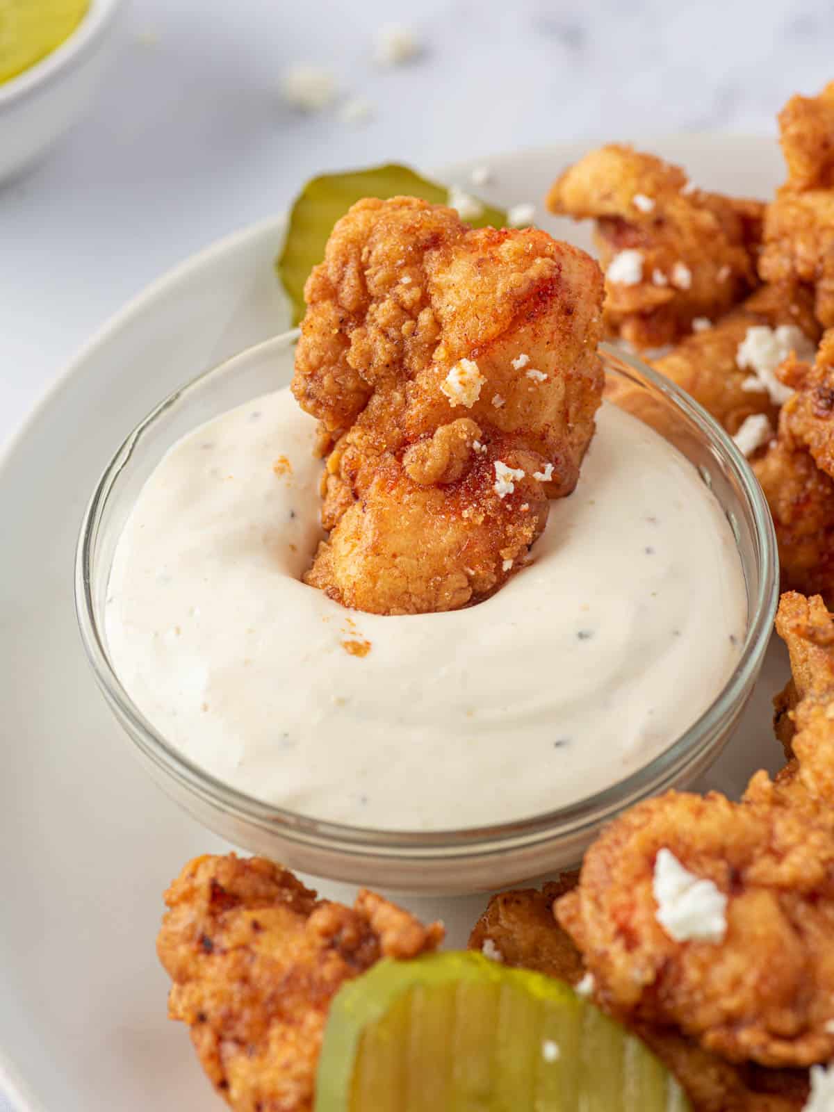 Nashville hot chicken tender dipped in sauce.