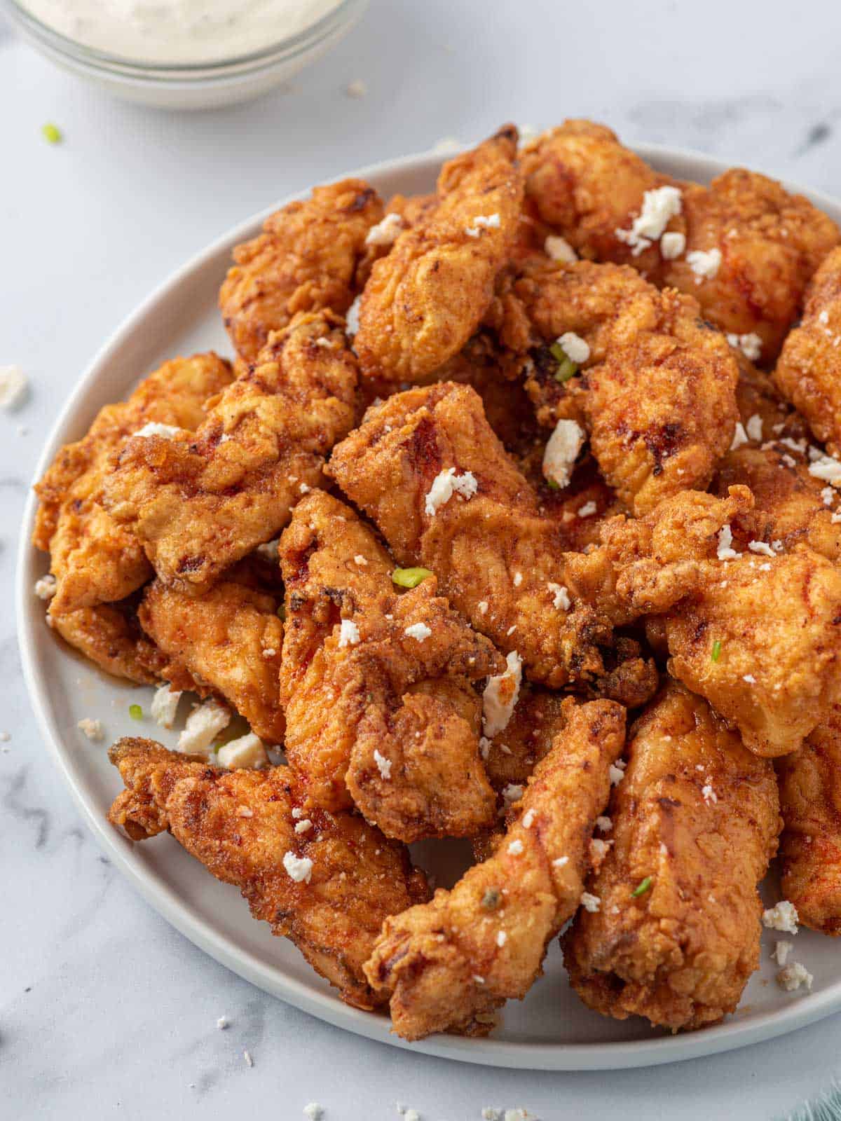 A plate of Nashville hot chicken tenders with crumbled cheese.