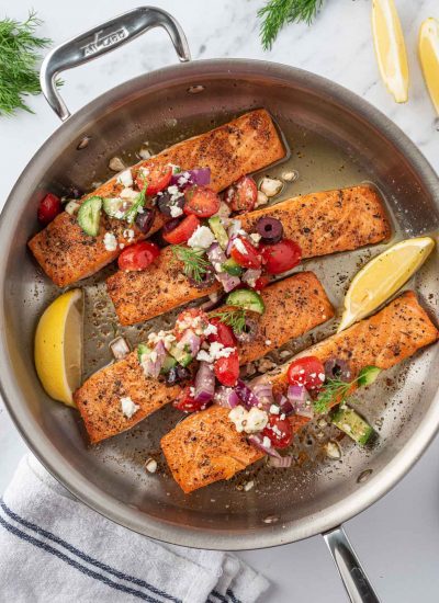 A skillet with grilled greek salmon and salsa.