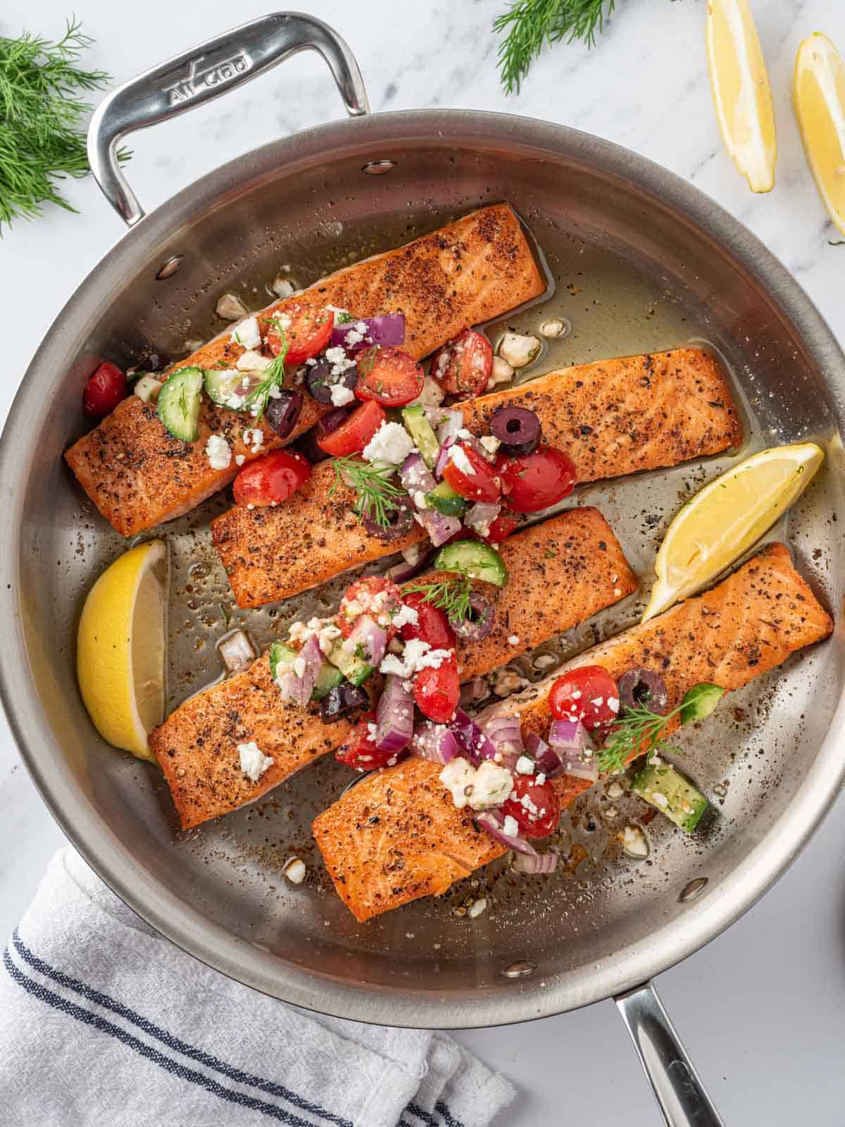 A skillet with grilled greek salmon and salsa.