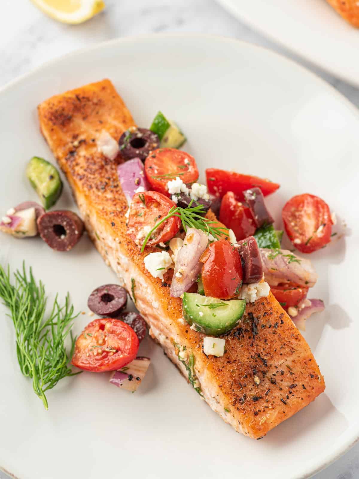Close up of a greek salmon fillet with salsa on top.