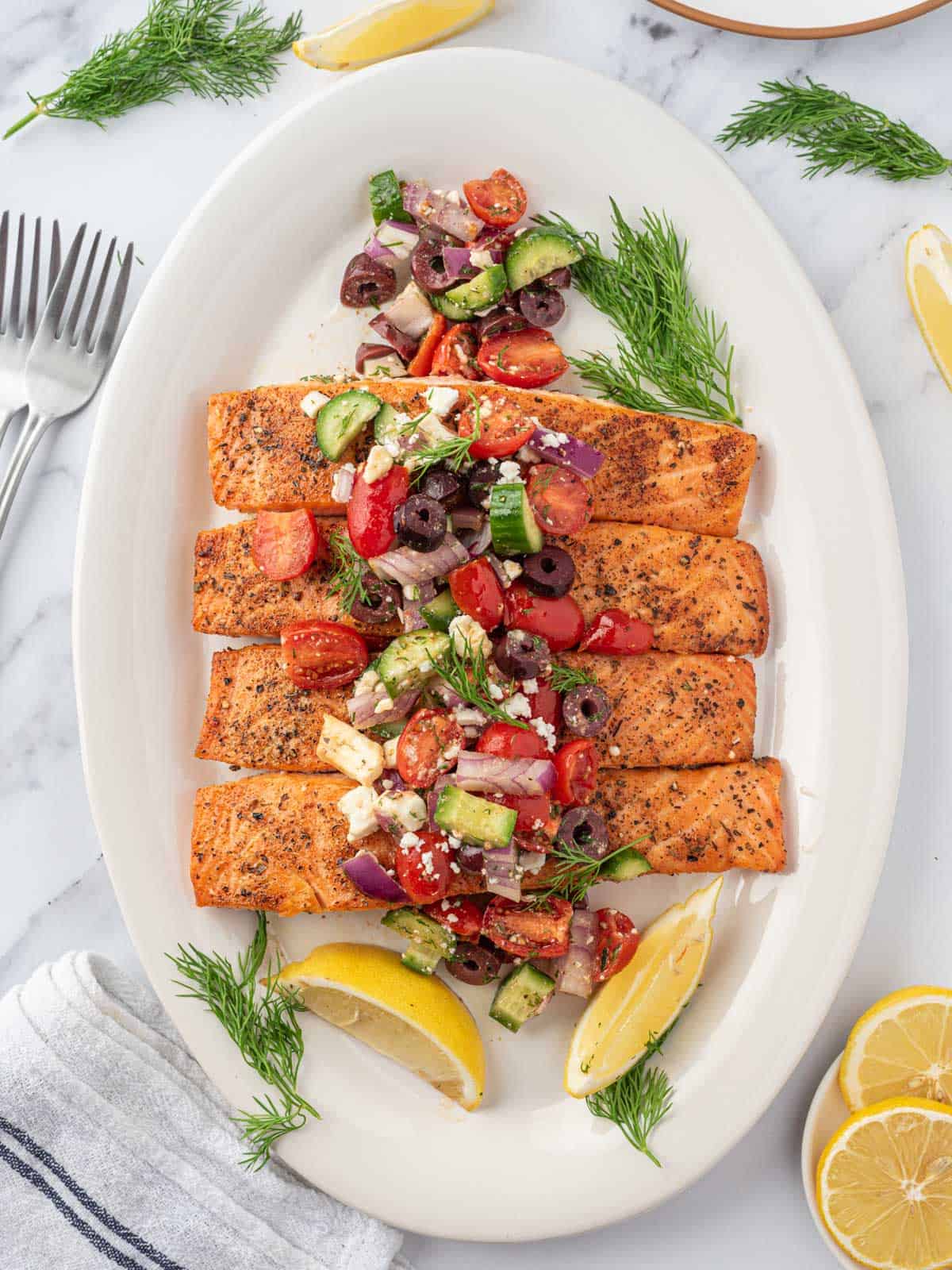 Greek salmon recipe served on a platter and topped with greek salsa.