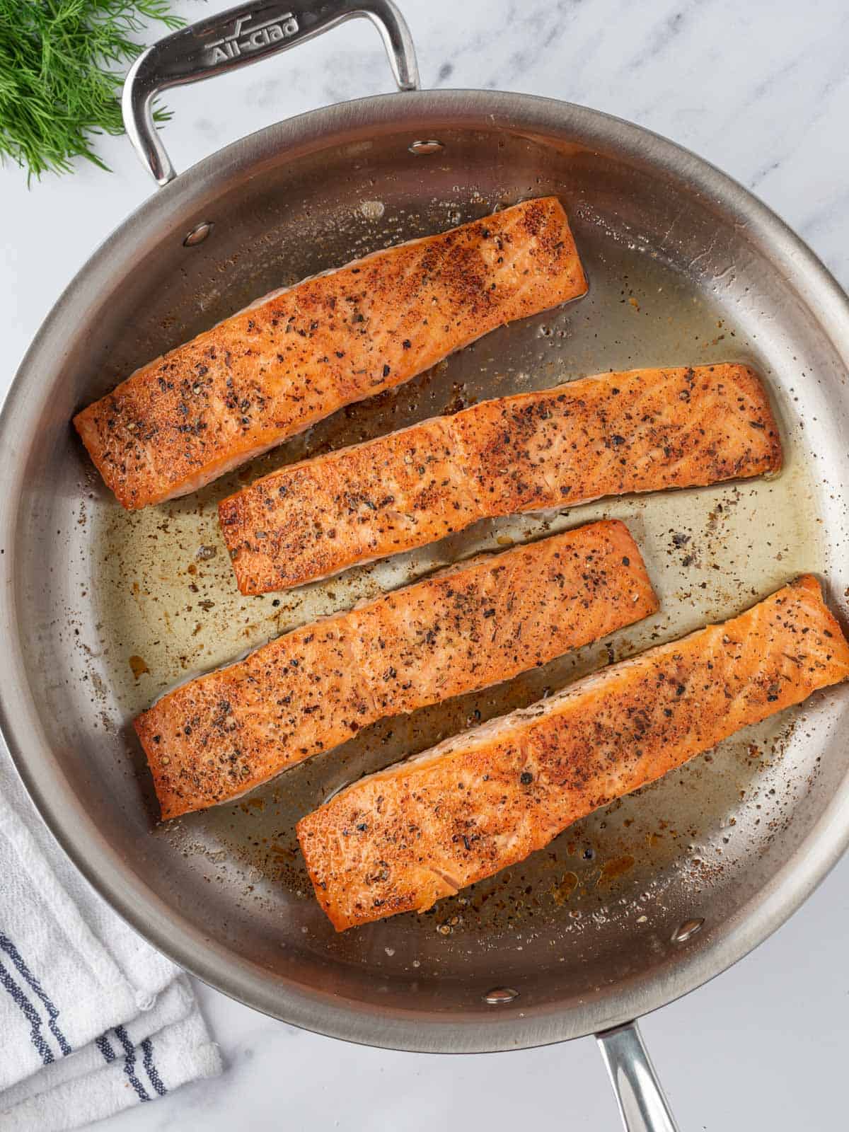 Salmon fillets seared in a pan.