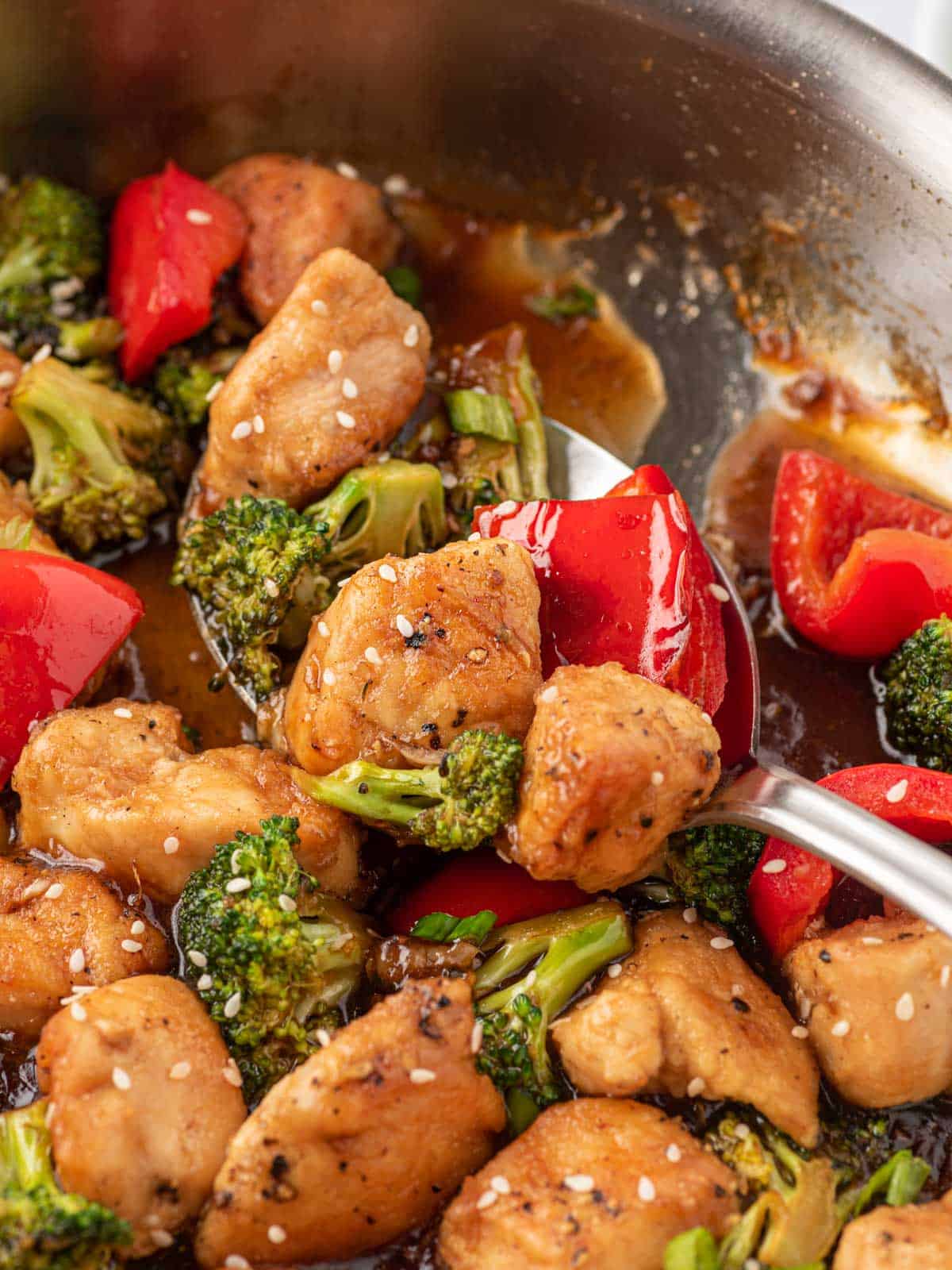 Easy chicken teriyaki stir fry on a spoon in a skillet.