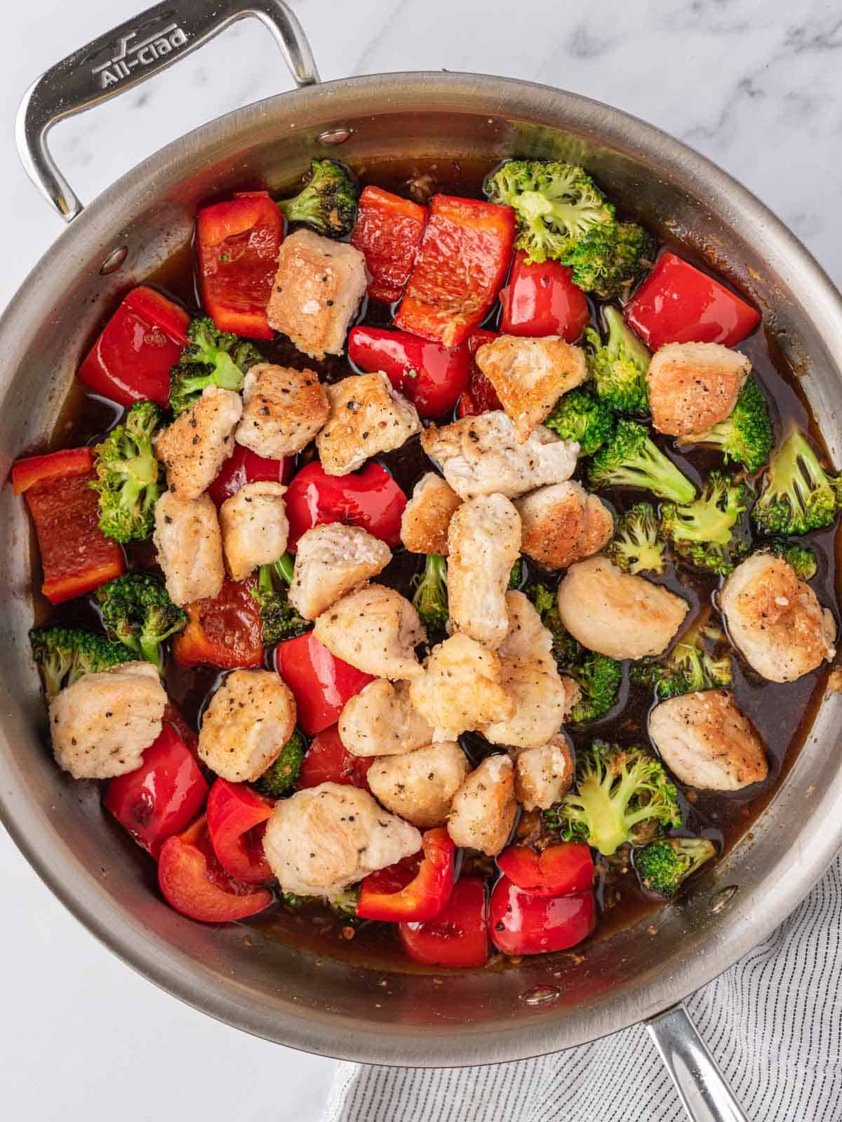 A skillet with Chicken, veggies and chicken stir fry sauce.