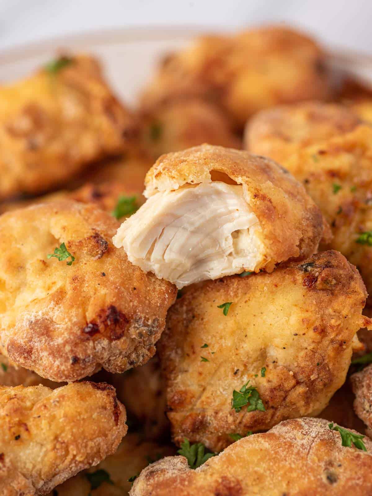 Close up of air fryer nuggets with a bite taken out of one.