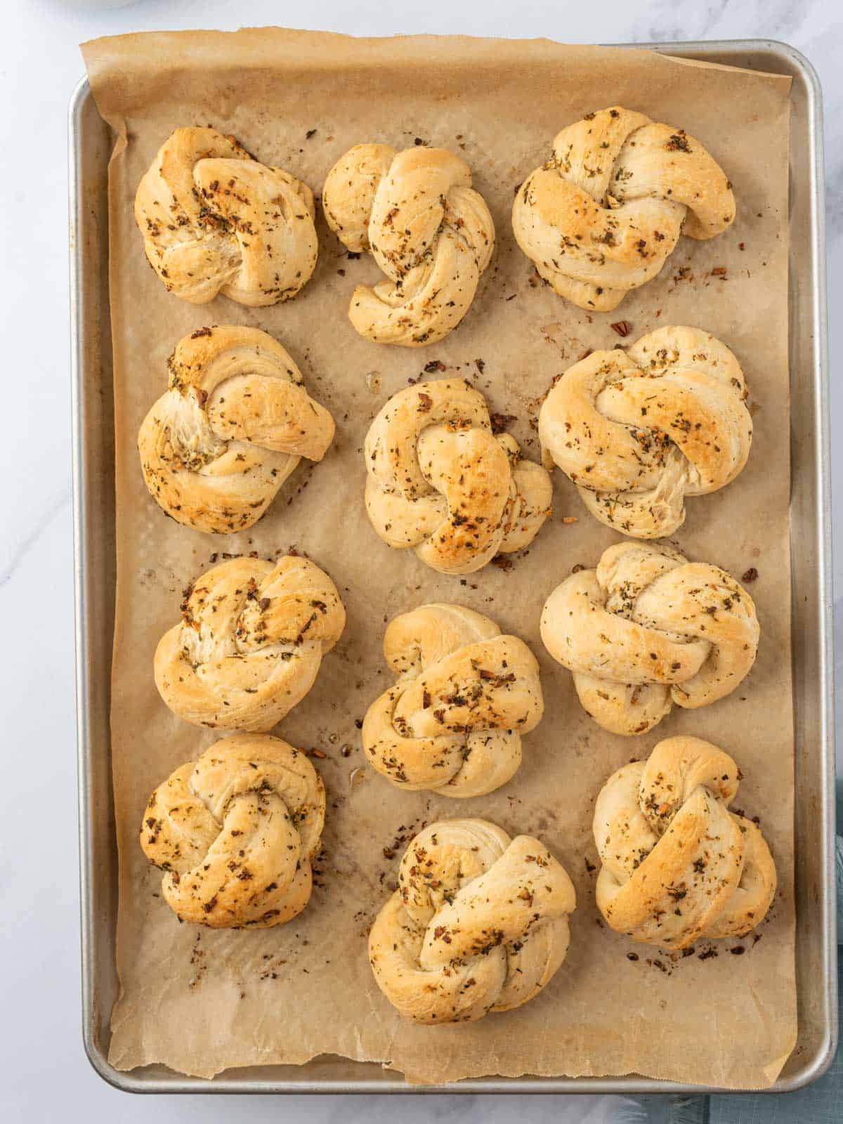 Baked knots with a light golden crust on a parchment-lined tray.