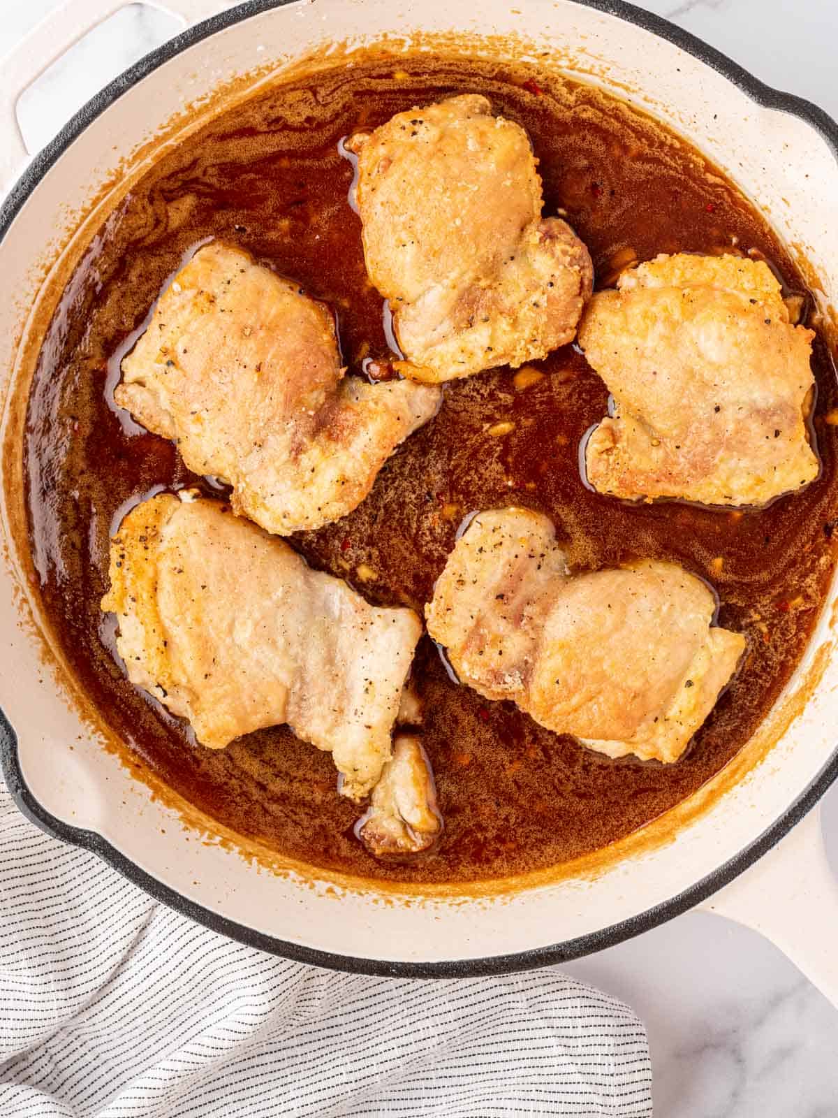 Chicken thighs cooking in sweet and spicy honey garlic soy sauce.