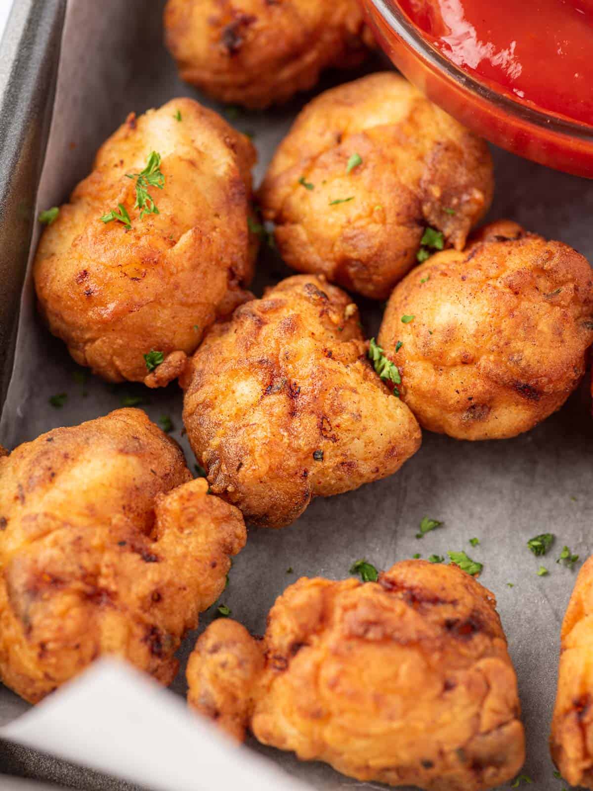 Pieces of fried popcorn chicken on a tray.