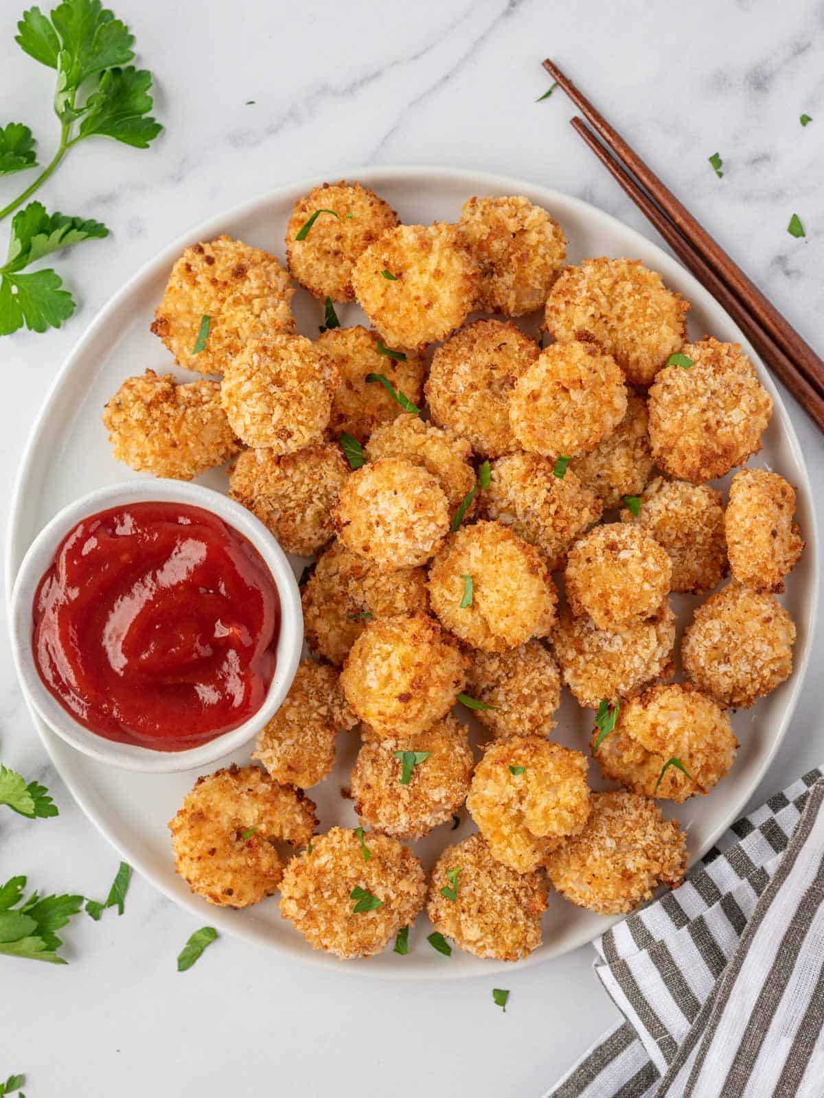 Cooked popcorn shrimp recipe on a round white tray with a bowl of dipping sauce.