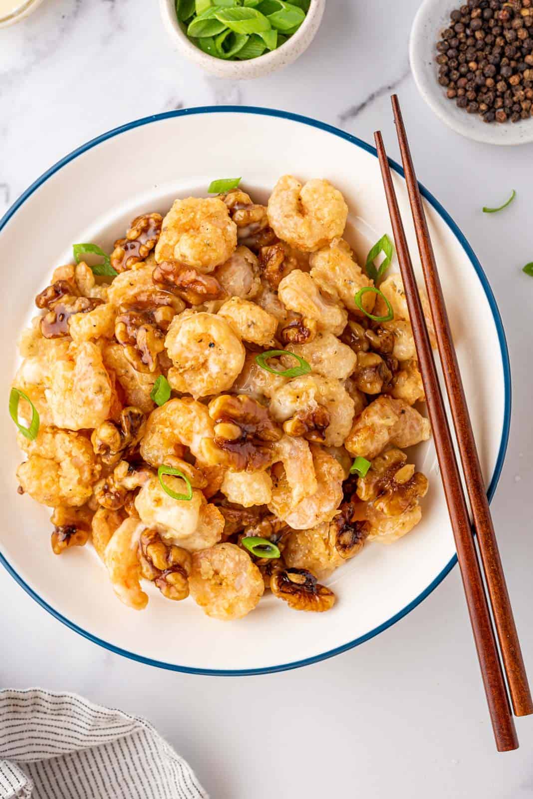 Walnut shrimp in a bowl with a pair of chopsticks.