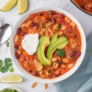 A bowl of easy vegan chili garnished with avocado, cilantro and vegan sour cream.