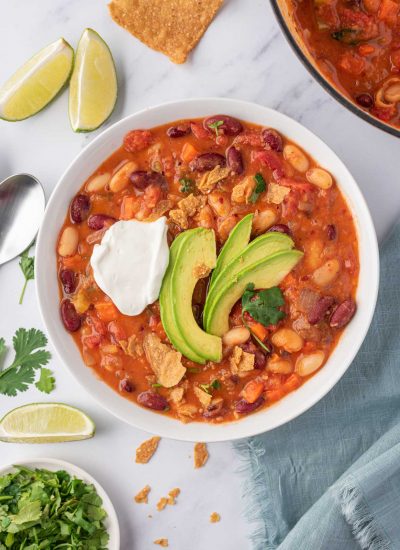 A bowl of easy vegan chili garnished with avocado, cilantro and vegan sour cream.