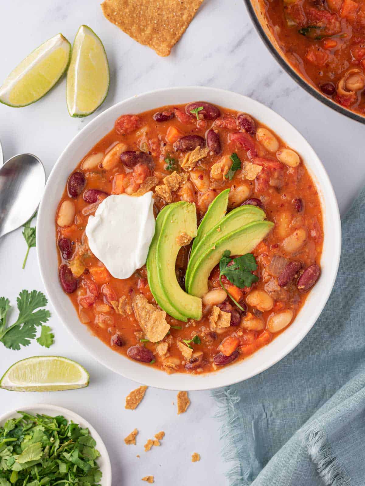 A bowl of easy vegan chili garnished with avocado, cilantro and vegan sour cream.