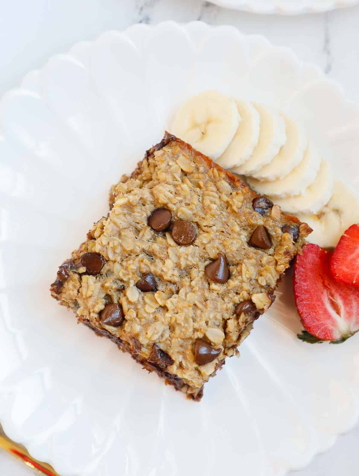 baked oatmeal with chocolate chips on a plate with fruit.