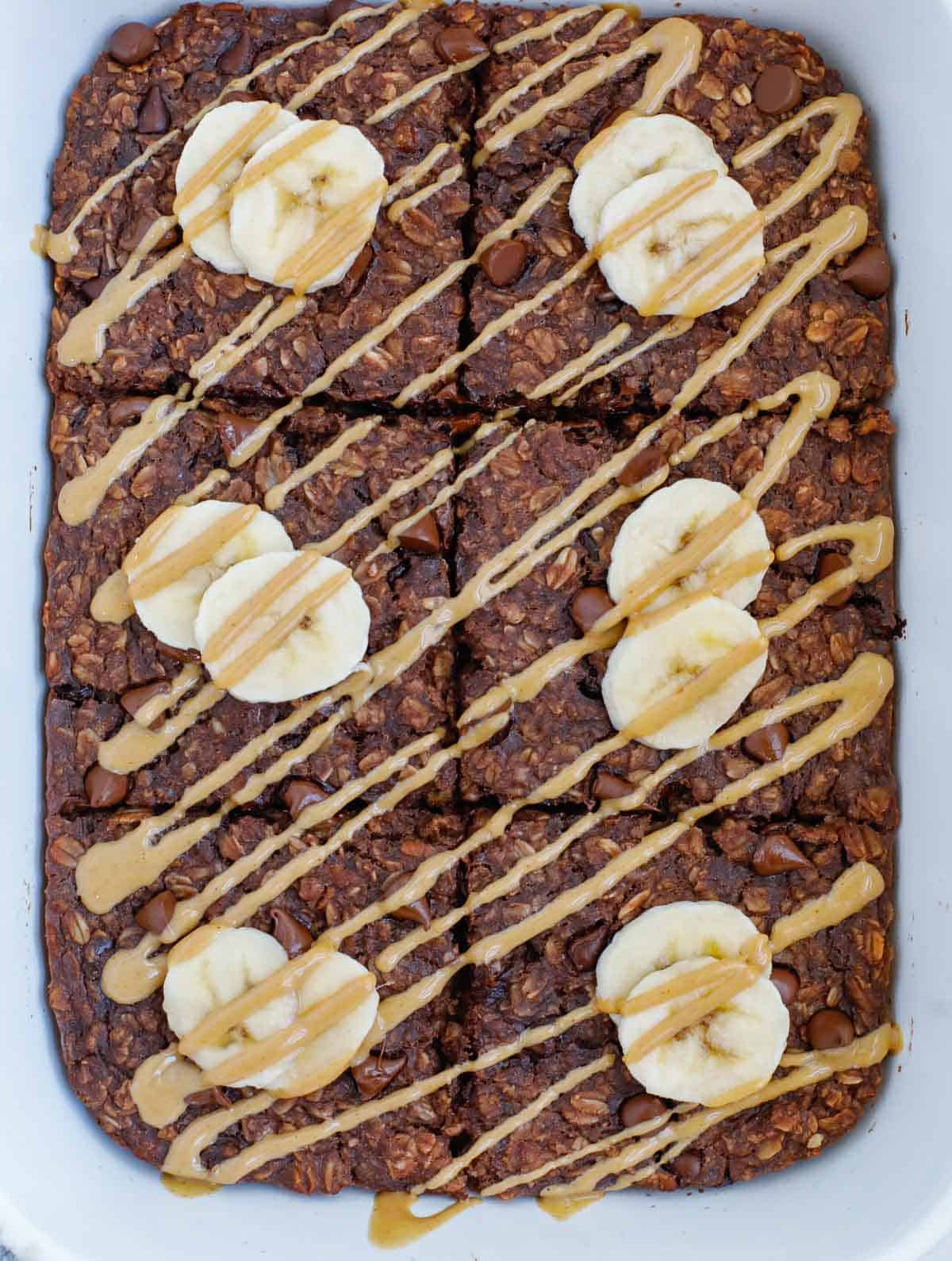 chocolate baked oats after baking, topped with fresh slices of banana and drizzle of peanut butter.