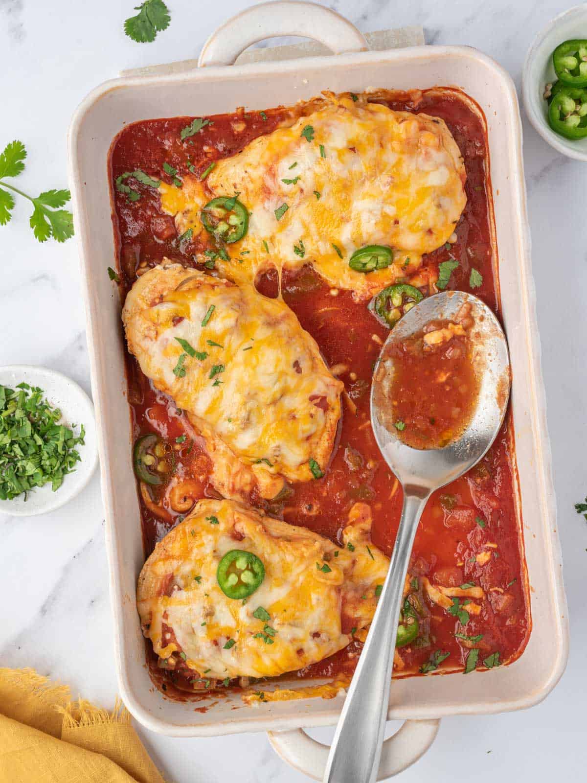 A baking dish with baked salsa chicken.