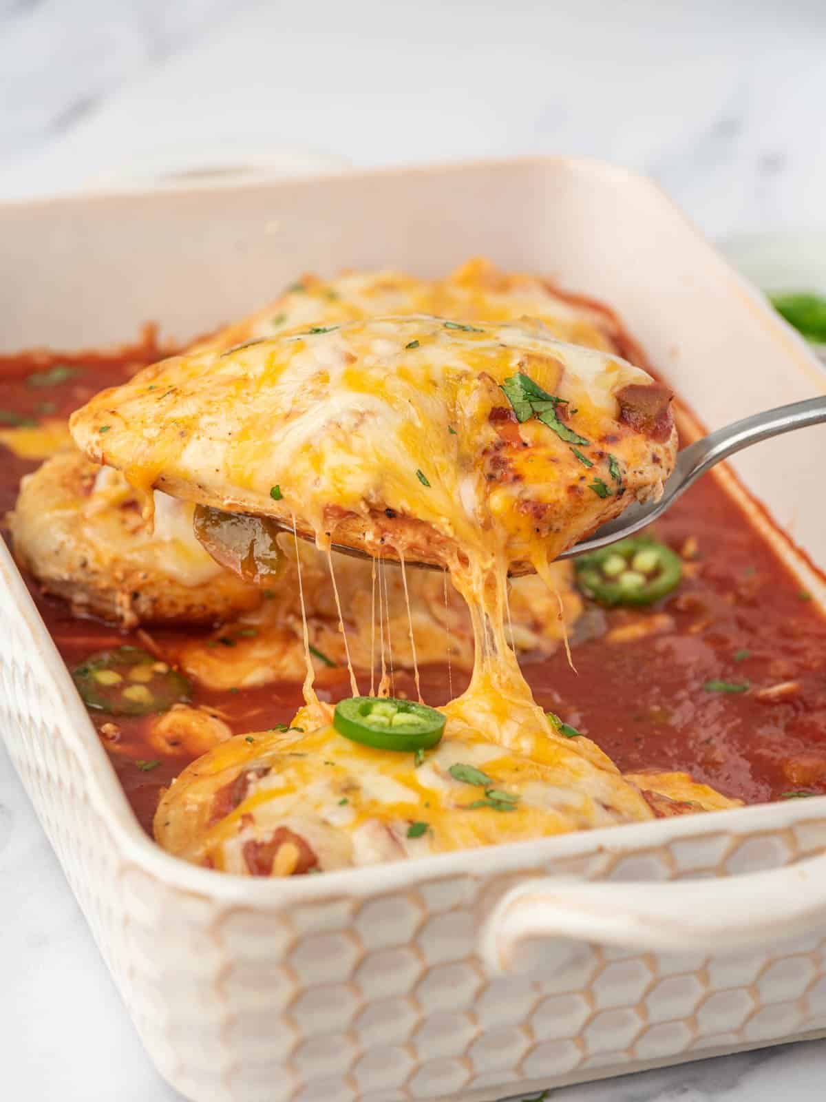 A serving of baked salsa chicken lifted from the baking dish.