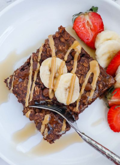 portion of a square baked oat topped with peanut butter, banana and strawberry