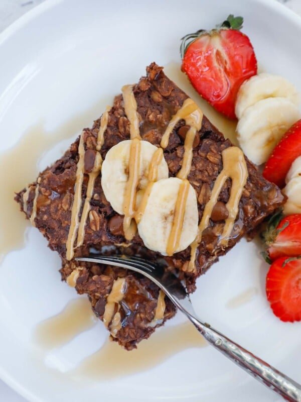 portion of a square baked oat topped with peanut butter, banana and strawberry