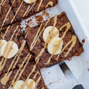 A slice of baked chocolate oatmeal sits in a baking dish.