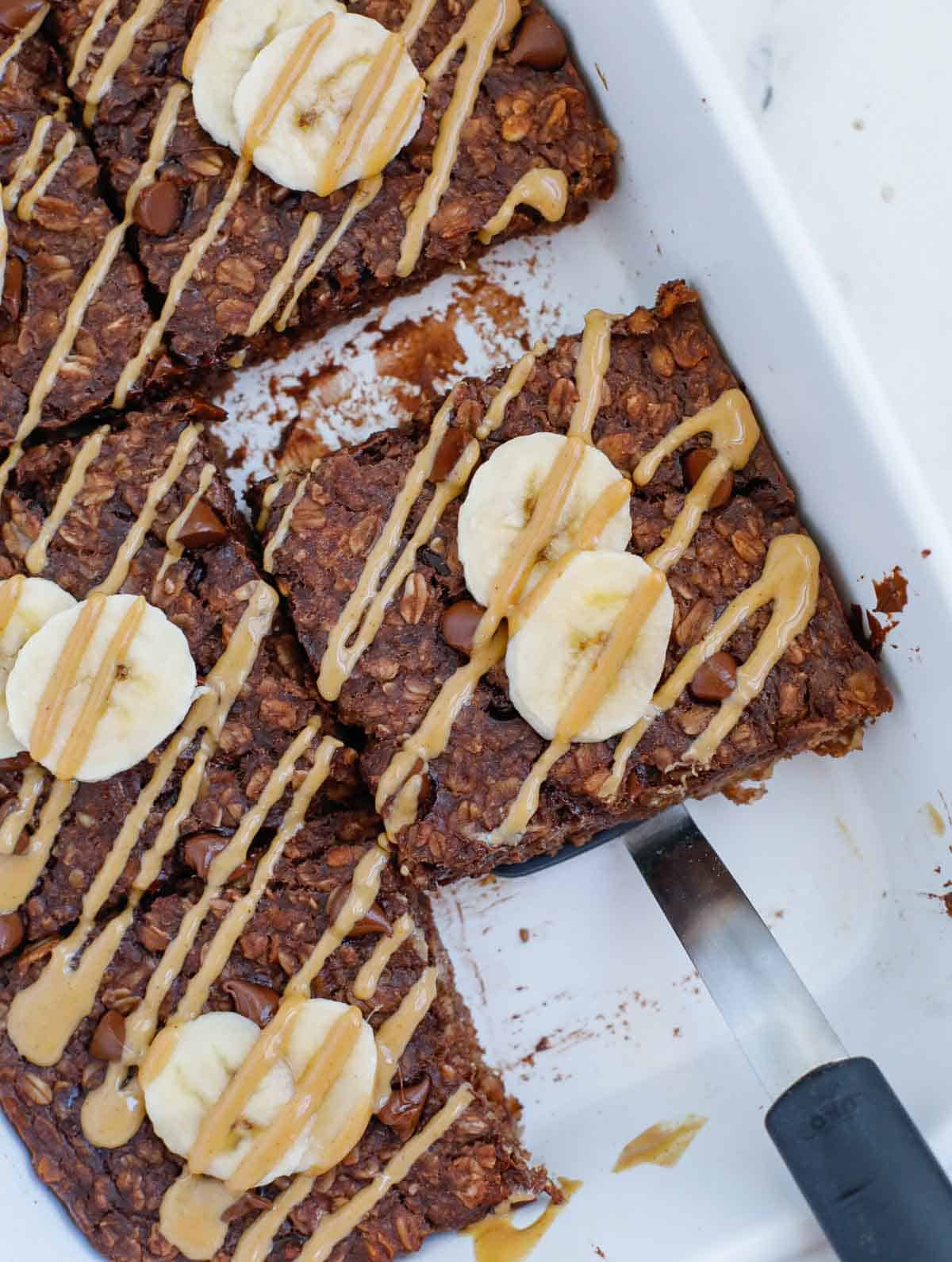 chocolate baked oats after baking, topped with fresh slices of banana and drizzle of peanut butter.