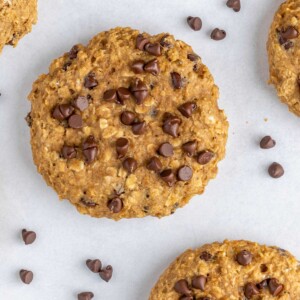 Overhead view of a healthy chocolate chip oatmeal cookie with chocolate chips scattered around.