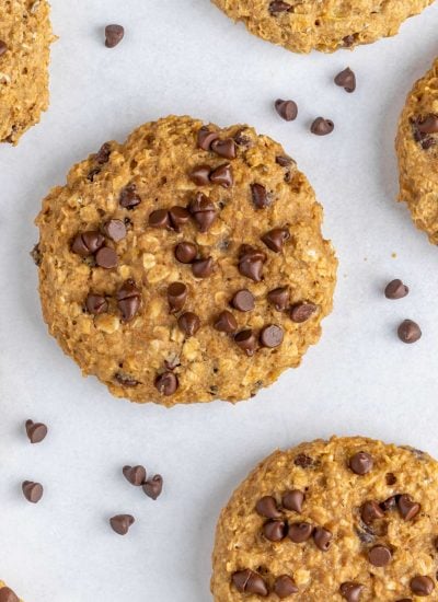 Overhead view of a healthy chocolate chip oatmeal cookie with chocolate chips scattered around.
