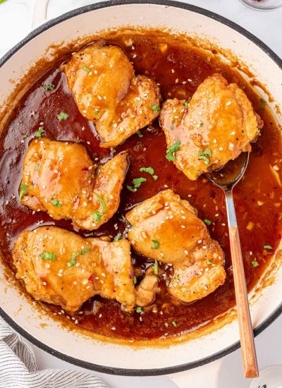 A pan of honey garlic chicken with a spoon under a chicken.