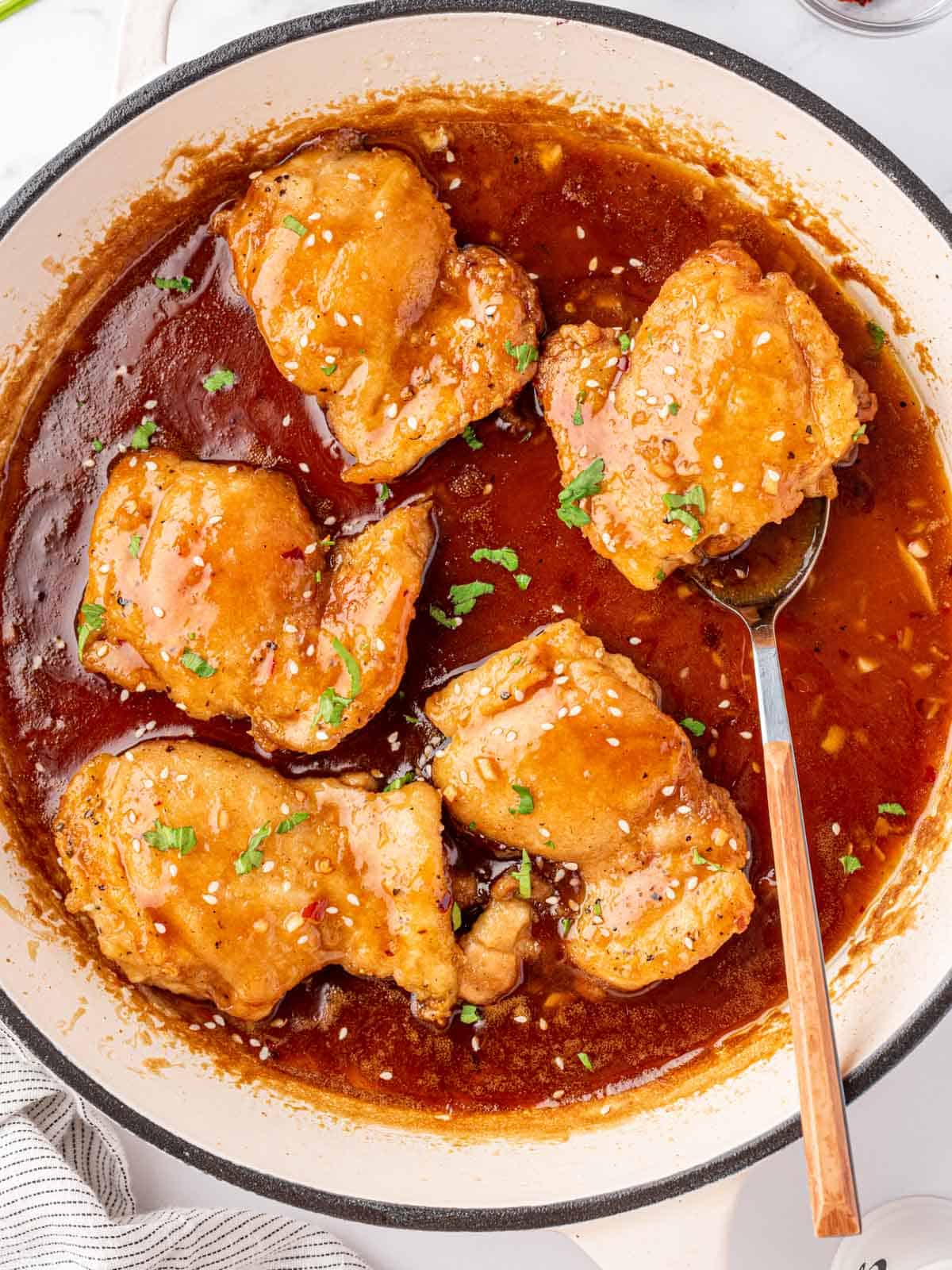 A pan of honey garlic chicken with a spoon under a chicken.