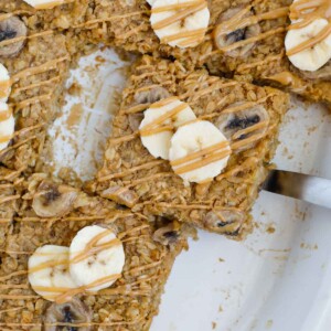 A slice of baked peanut butter banana oatmeal lifted out of a baking dish.