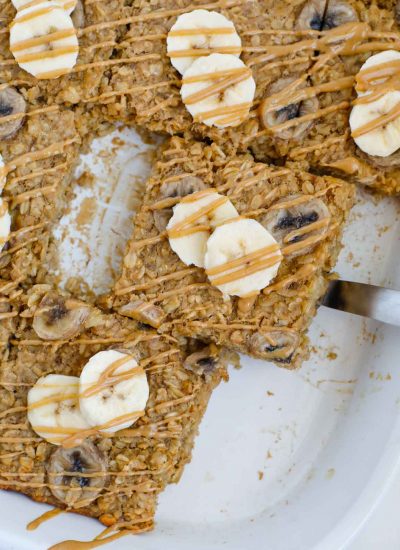 A slice of baked peanut butter banana oatmeal lifted out of a baking dish.