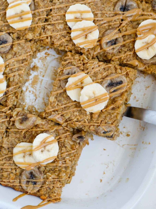 A slice of baked peanut butter banana oatmeal lifted out of a baking dish.